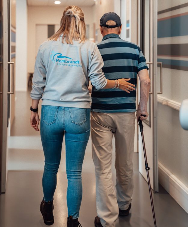 Fysiotherapeut helpt man met wandelen met artrose in de gang