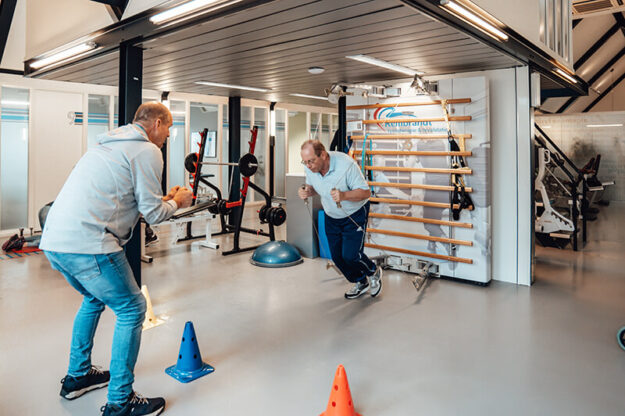Man doet oefeningen bij therapeut Hans Bloo tijdens sportfysiotherapie in de oefenzaal met een rek Rembrandt Fysiotherapie & Revalidatie Veenendaal Amerongen Duiven Rhenen Lienden