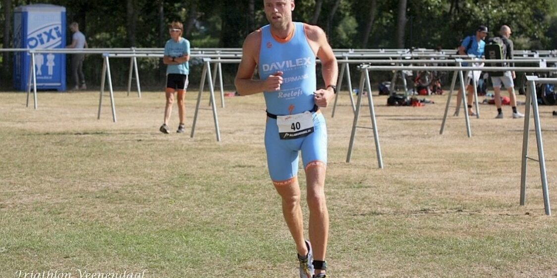 zweepslag Atleet in een blauw renpak voorkomt een zweepslag aan de kuit en doet mee met een wedstrijd triatlon.