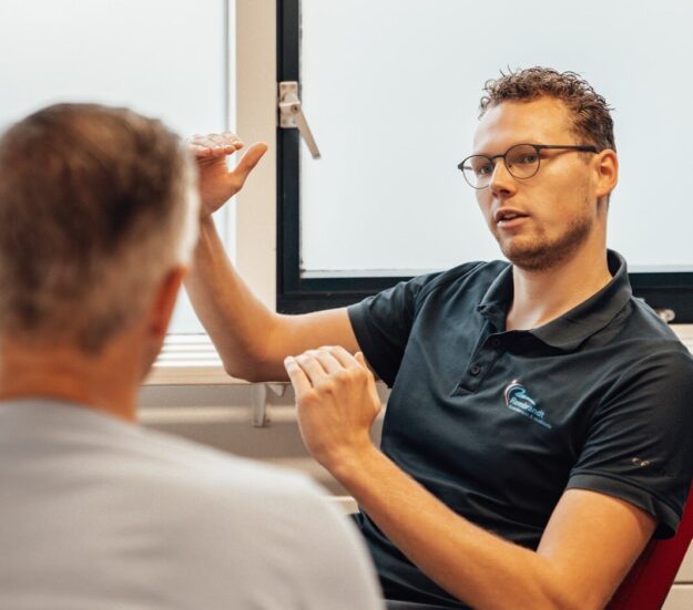 Therapeut geeft uitleg aan een man over ischias