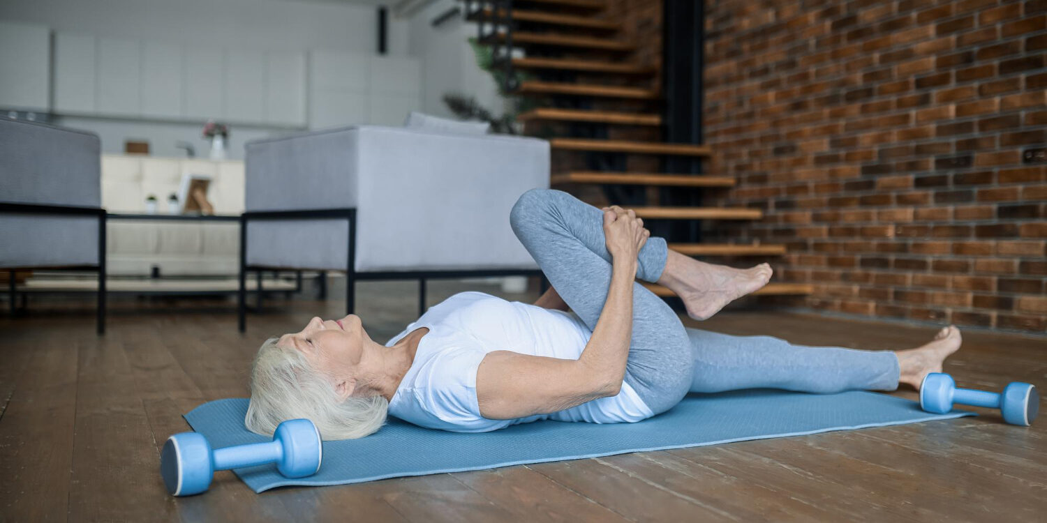 vrouw werkt aan haar knakkende knieën door oefeningen te doen in haar woonkamer op een yogamat.