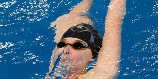 Voordelen van zwemmen Een dame meteen badmuts en duikbril op haar hoofd in het zwembad de rugslag aan het doen om te profiteren van de voordelen van zwemmen