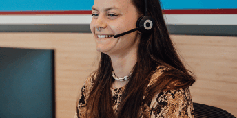 vrouw die achter de computer zit met headset op