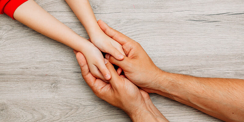 Handen van ouder en kind ineen